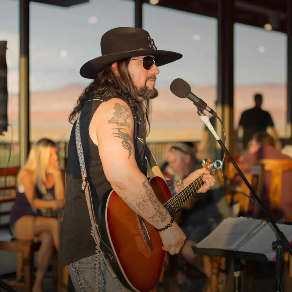 Image of man in sunglasses and hat playing guitar